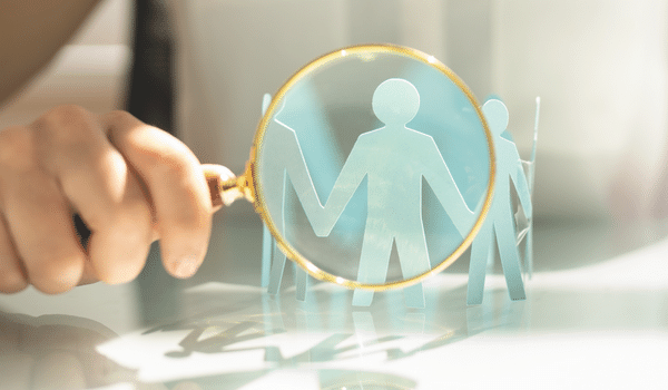 Paper cutout of people and a magnifying glass on one
